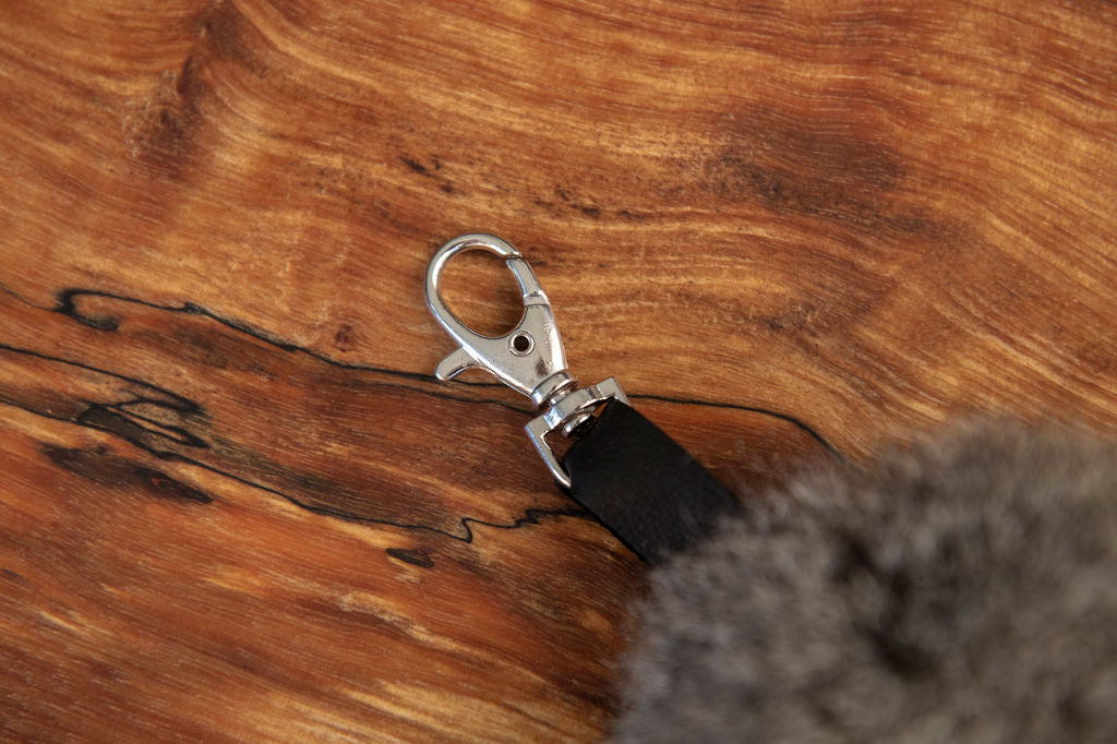 Metal clip with black leather strap on a wooden surface